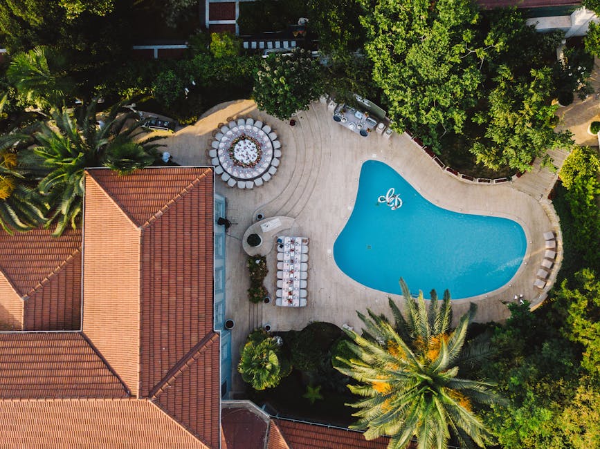 Μια εκπληκτική αεροφωτογραφία ενός τροπικού θέρετρου με πισίνα και πλούσιο πράσινο.